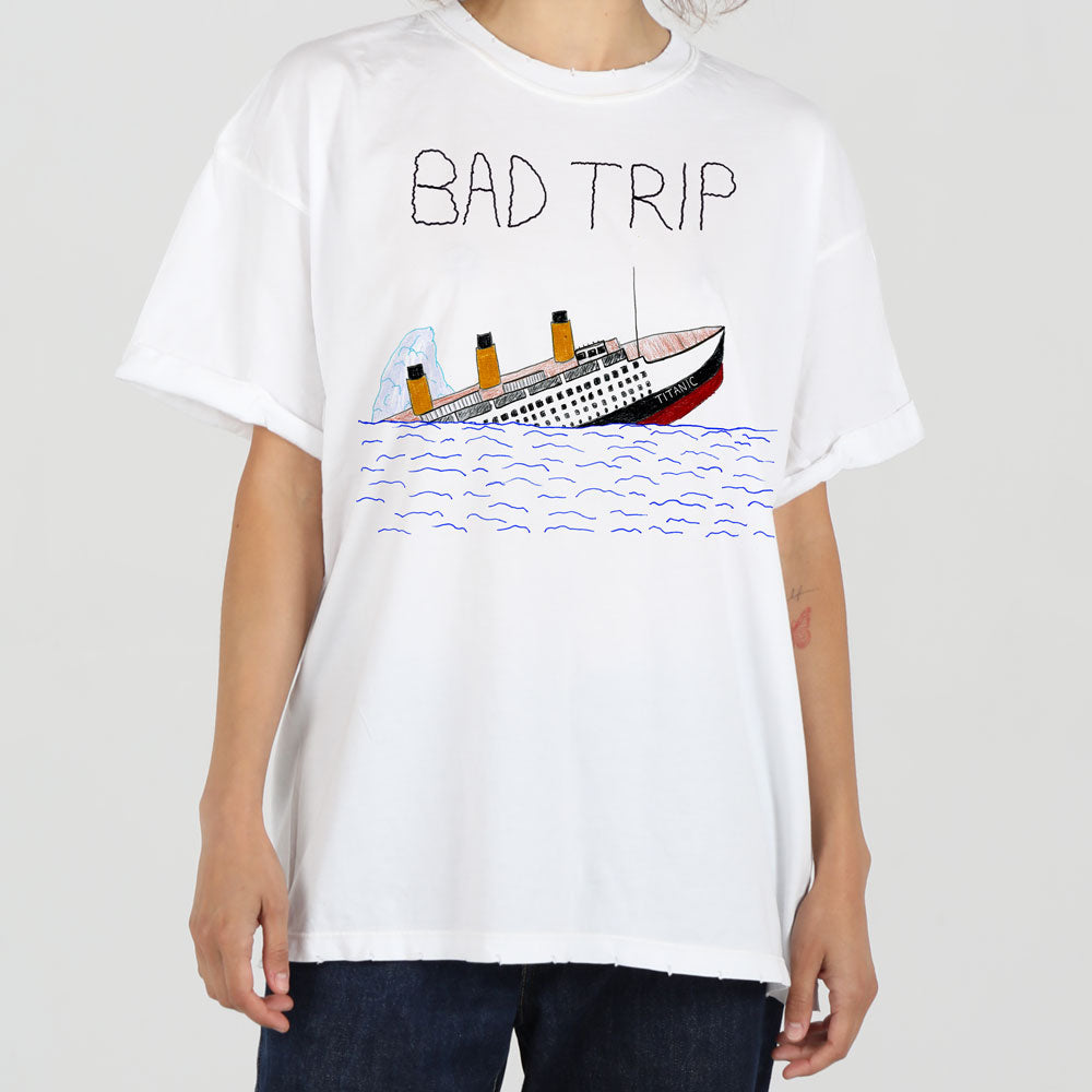 A person in a white t-shirt featuring a graphic of a sinking ship with the text "bad trip" above it. the person is facing forward and the background is plain.