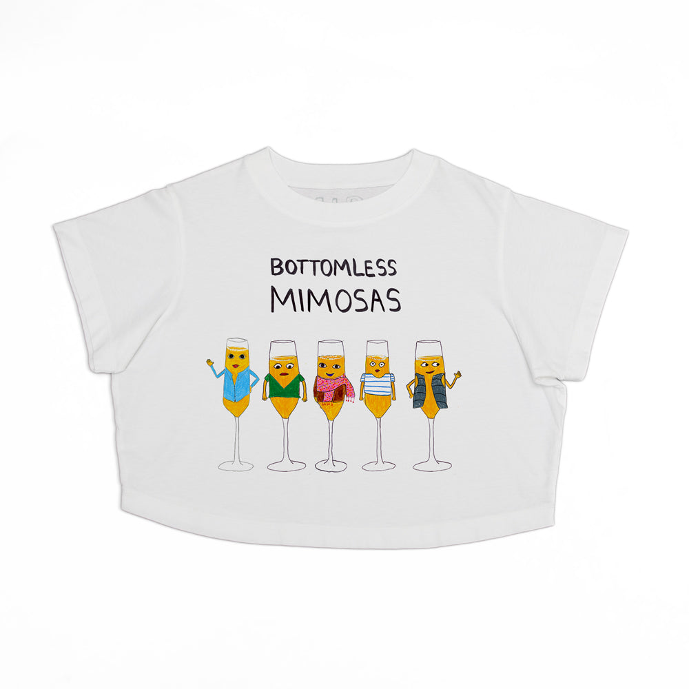 White cropped t-shirt with a fun design featuring cartoon mimosa glasses, each with a different expression and accessories, and the text "bottomless mimosas" above them.