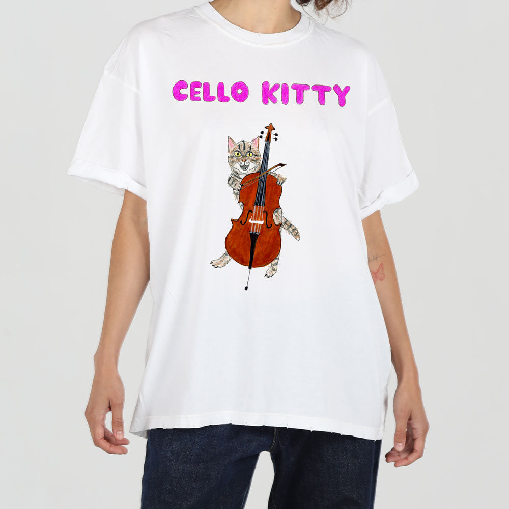 A person models a white t-shirt featuring a whimsical graphic of a cat playing a cello, with the text "cello kitty" in purple above the image.