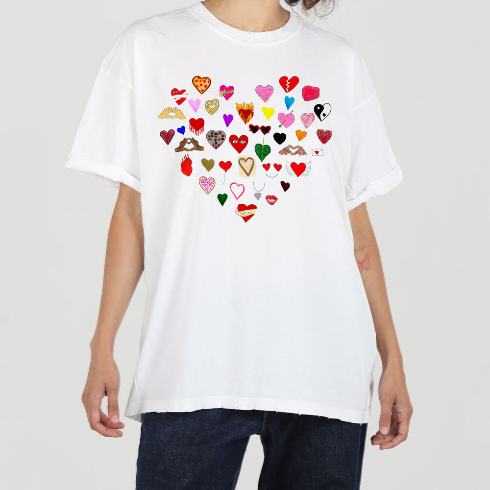 A person wearing a white t-shirt featuring a heart-shaped design made up of various colorful and patterned hearts, standing against a plain background.