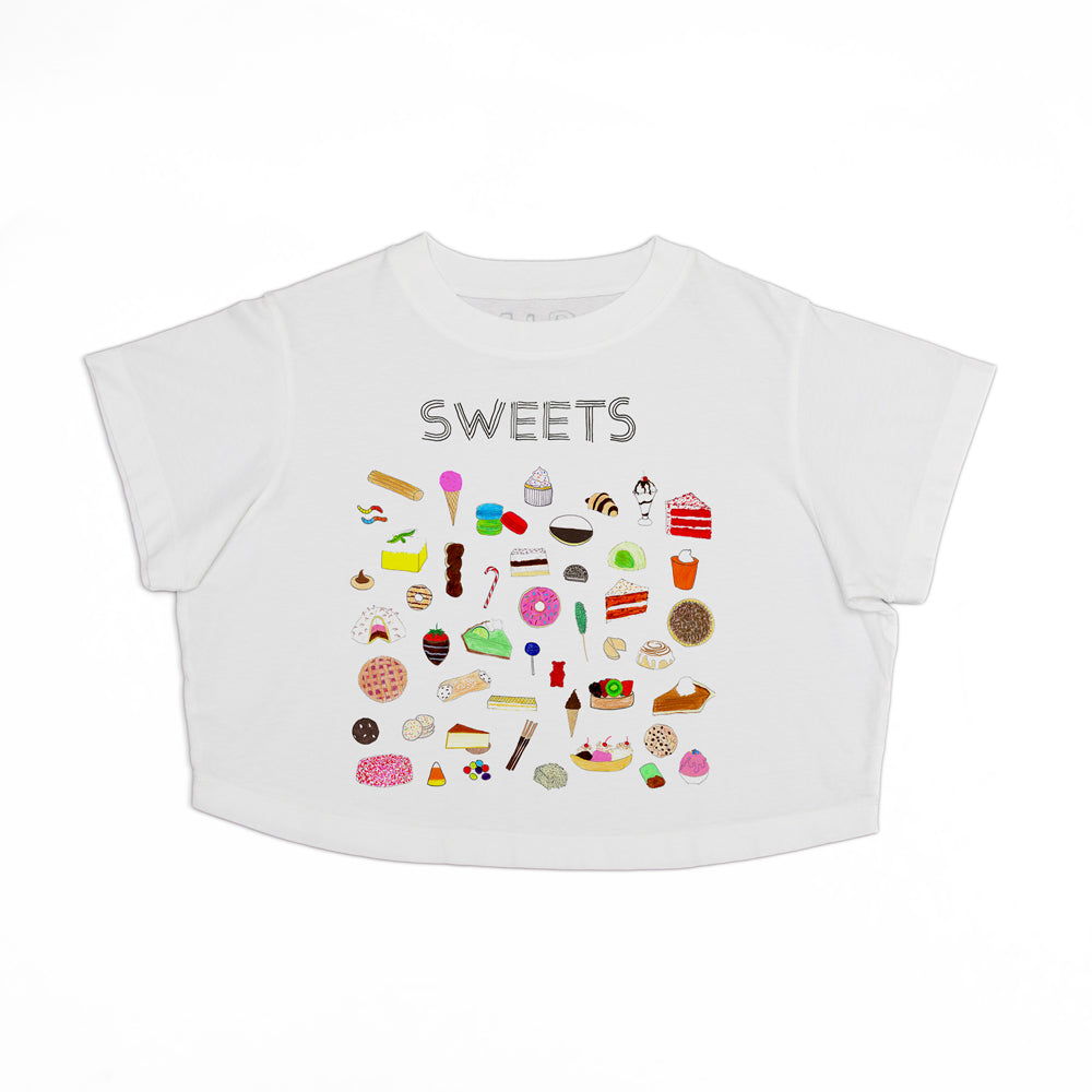 A white children's t-shirt with a colorful array of various sweet food items printed on the front, including ice cream, cupcakes, and candies, displayed on a plain background.
