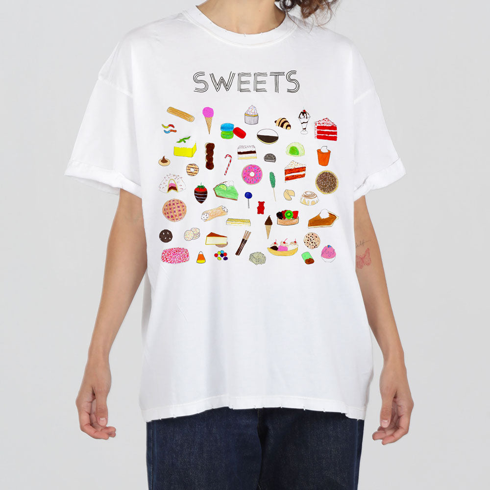 A person wearing a white t-shirt with an assortment of colorful sweet treats graphics including ice cream, cupcakes, and candies.