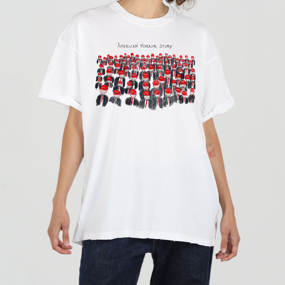 A person in a plain white t-shirt with a graphic print titled "american horror story," featuring rows of small, red, identical figures, stands against a light background.
