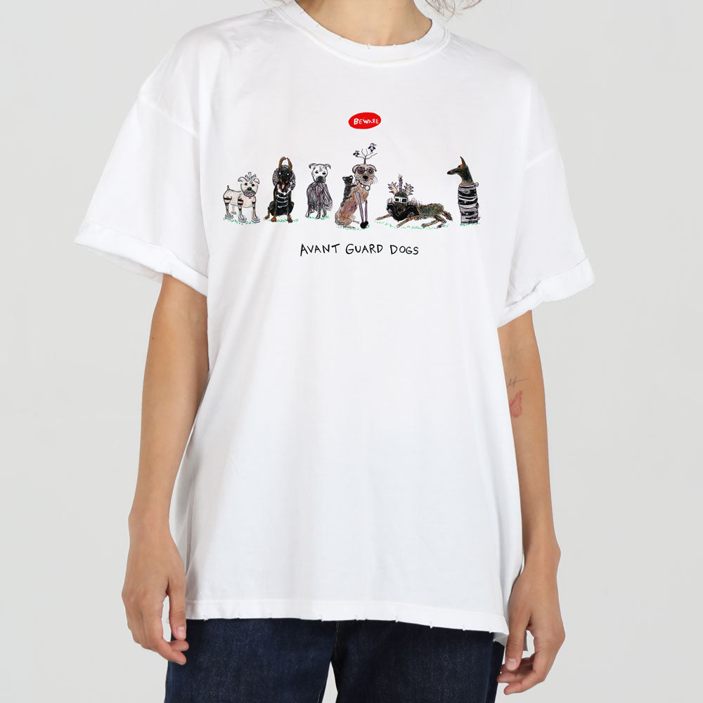 A person wearing a white oversized t-shirt with a design that reads "avant guard dogs," featuring illustrations of various dogs in artistic, fashionable costumes.