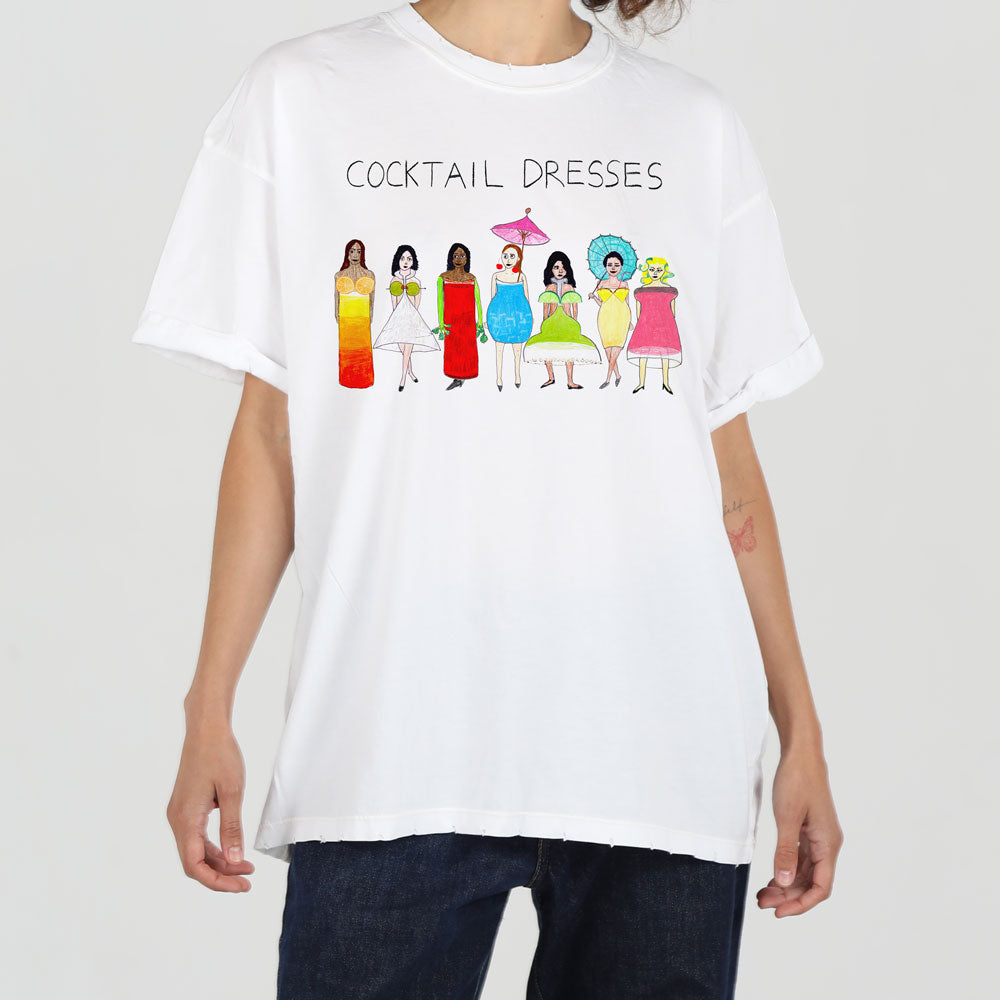 A person wearing a white t-shirt with a colorful design featuring seven cartoon-style women wearing different styled and colored cocktail dresses, titled "cocktail dresses".