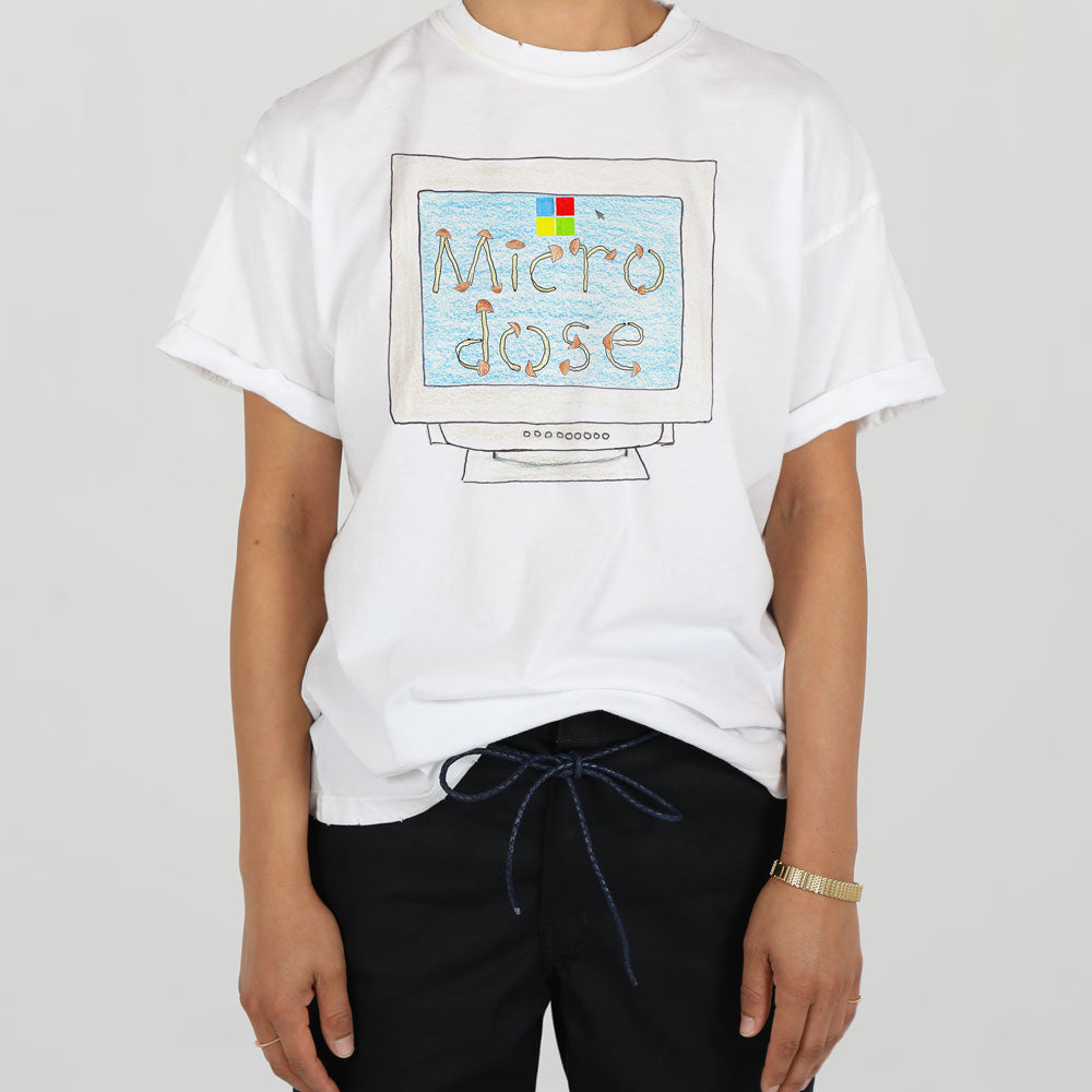 A person wearing a white t-shirt with "micro dose" graphic print, paired with casual navy drawstring trousers.