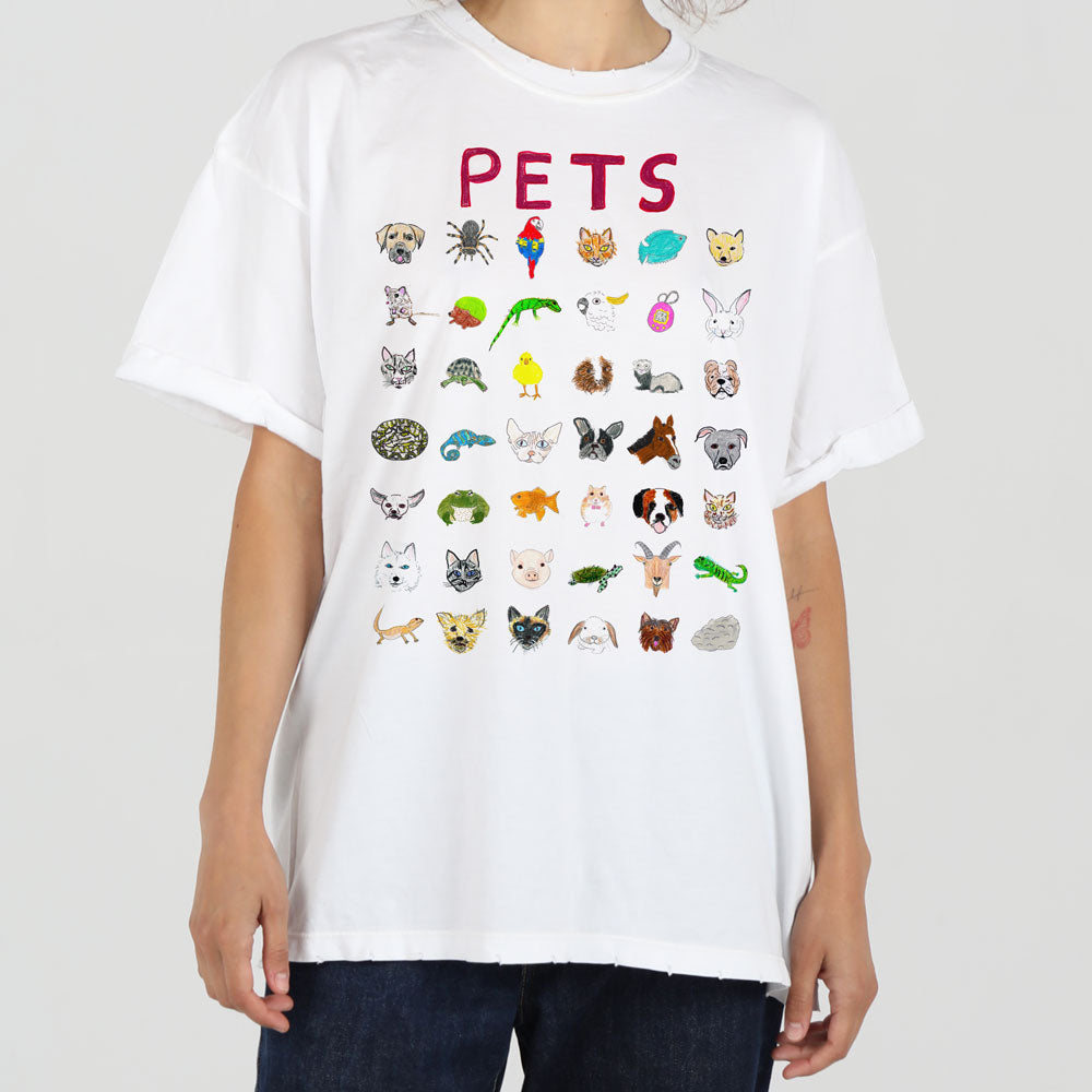A person in a white t-shirt that features a colorful array of animal illustrations under the word "pets." the shirt includes cats, dogs, birds, and small mammals.