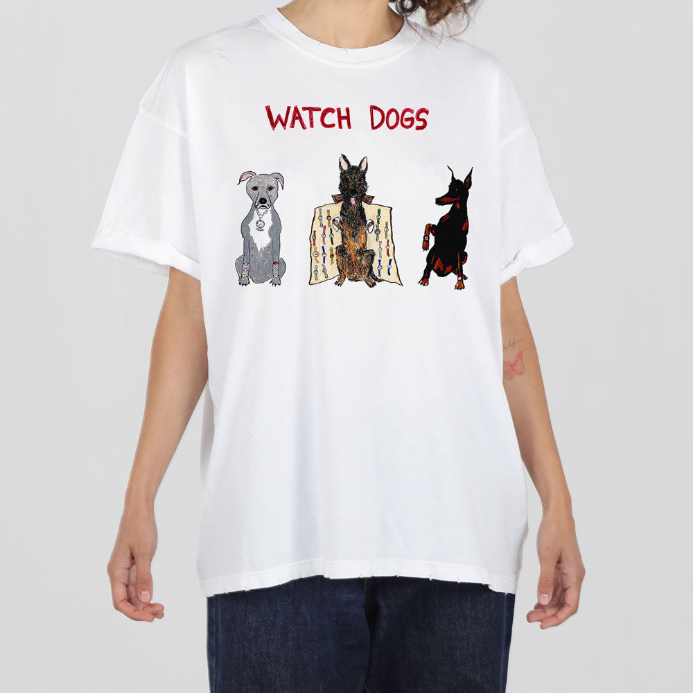 A person wears a white t-shirt featuring the text "watch dogs" above illustrations of three stylized dogs in different poses and colors.