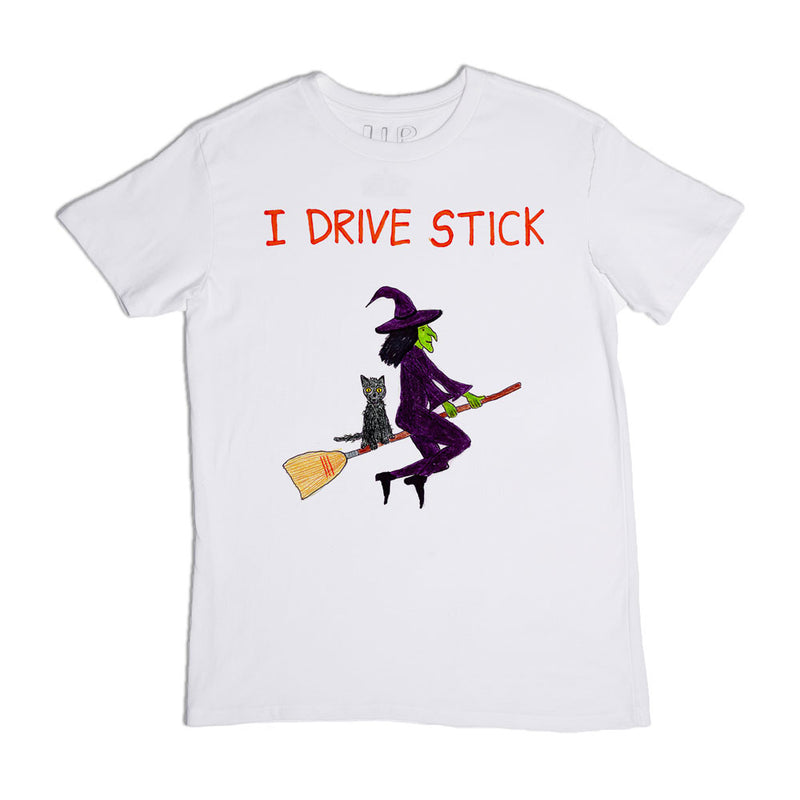 White t-shirt featuring a graphic of a witch riding a broomstick with a cat, along with the text "i drive stick" in red above the image.