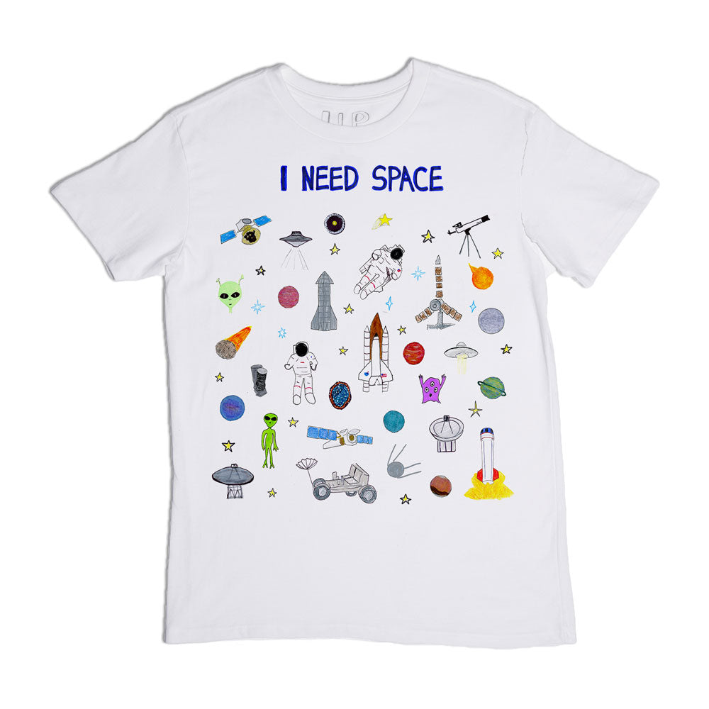 A white t-shirt with the phrase "i need space" printed in blue at the top, surrounded by colorful space-themed graphics including planets, astronauts, spaceships, and rockets.