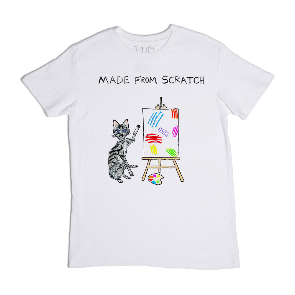 A white t-shirt featuring a design of a cat with painted stripes, sitting next to an easel with a colorful abstract painting, captioned "made from scratch.