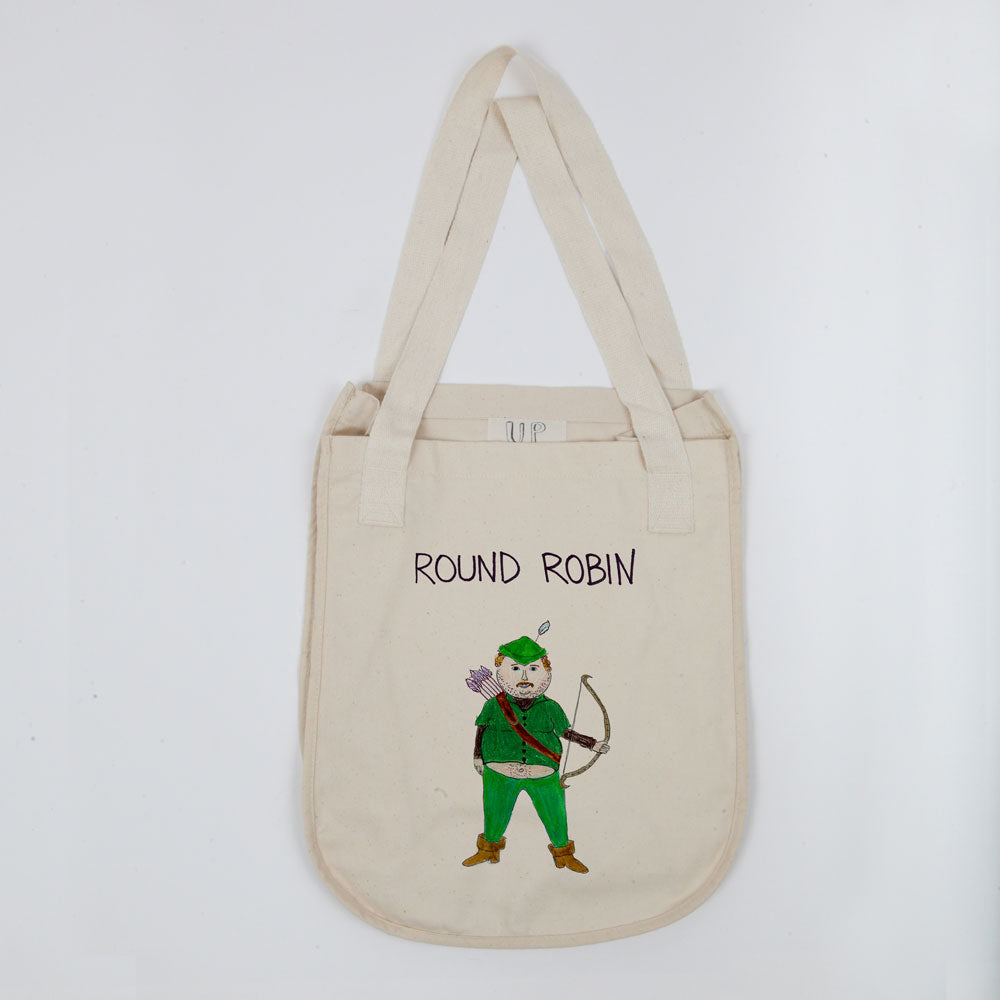 A beige canvas tote bag with "round robin" written at the top. it features an illustration of a robin in a green jacket and hat, holding a bow and arrow. the bag has a long shoulder strap.