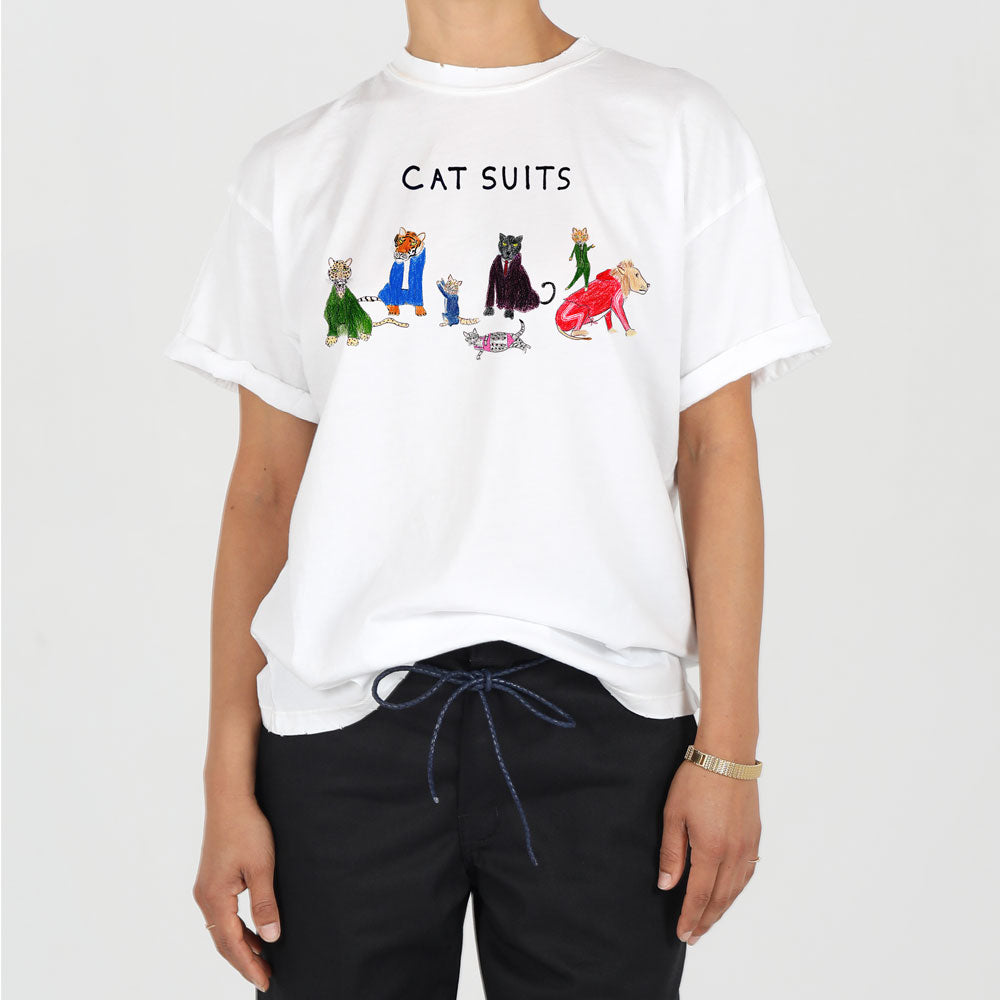 A person wearing a white t-shirt with "cat suits" printed on it, featuring illustrations of cats in various colorful outfits. only the torso and arms of the person are visible.