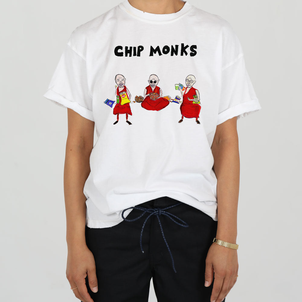 A person wearing a white t-shirt with a graphic that reads "chip monks," featuring three monks in traditional robes, each holding a computer chip.