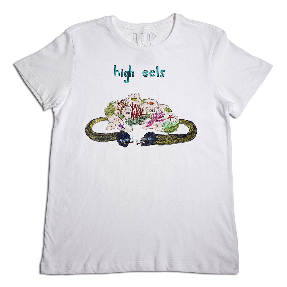 White t-shirt with an illustrated design featuring the words "high eels" above a whimsical, colorful drawing of a mountain landscape inside a loop resembling a belt with high heel shoes at the ends.