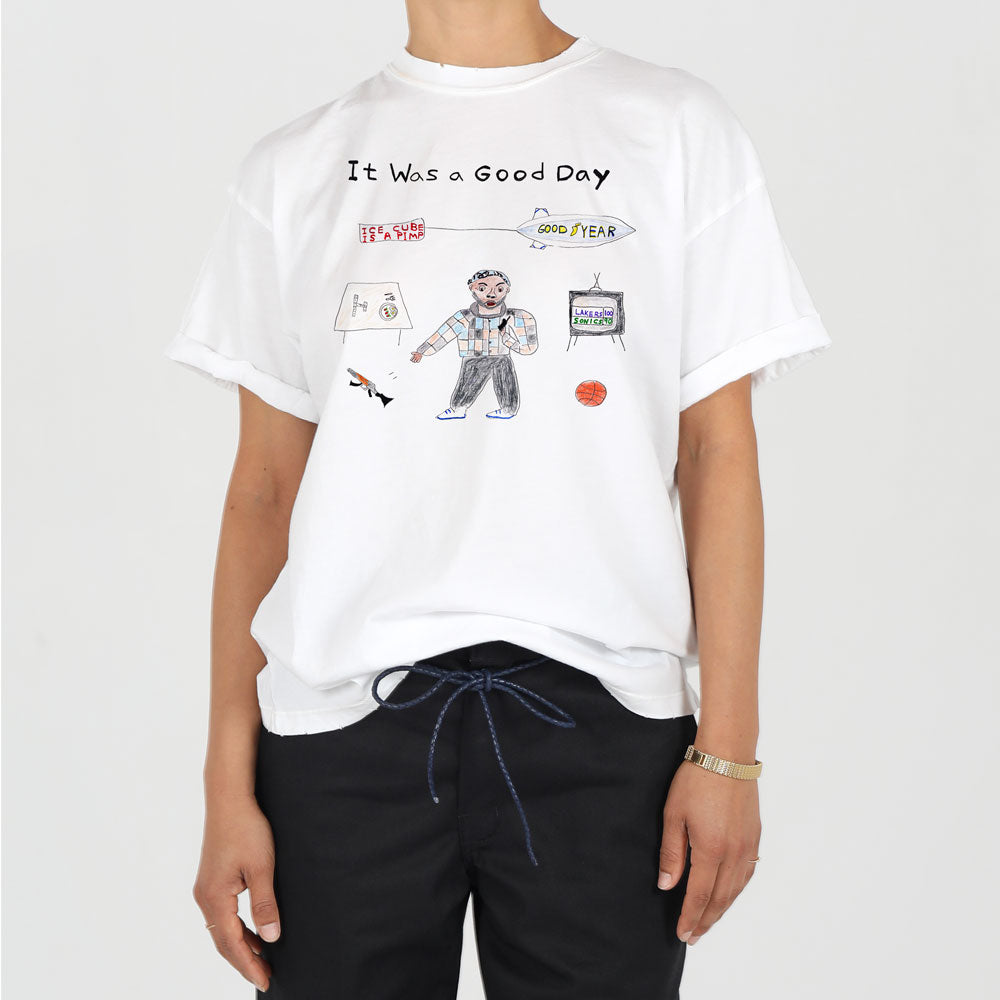 A person wearing a white t-shirt with a graphic design captioned "it was a good day," featuring drawings of a man, burger, basketball, and other icons. the shirt is paired with black pants tied with a blue drawstring.