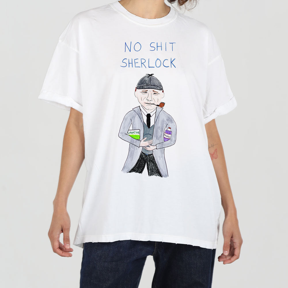 A person wearing a white t-shirt with a graphic print. the print features a detailed drawing of a classic detective holding a magnifying glass, under the phrase "no shit sherlock" in capitalized bold letters.