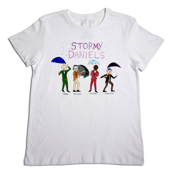 A white t-shirt featuring a graphic with four cartoon-style figures under colorful umbrellas and text "stormy daniels" at the top. each figure is labeled with playful names like "craig," "dwayne," "kevin," and "rajulie.