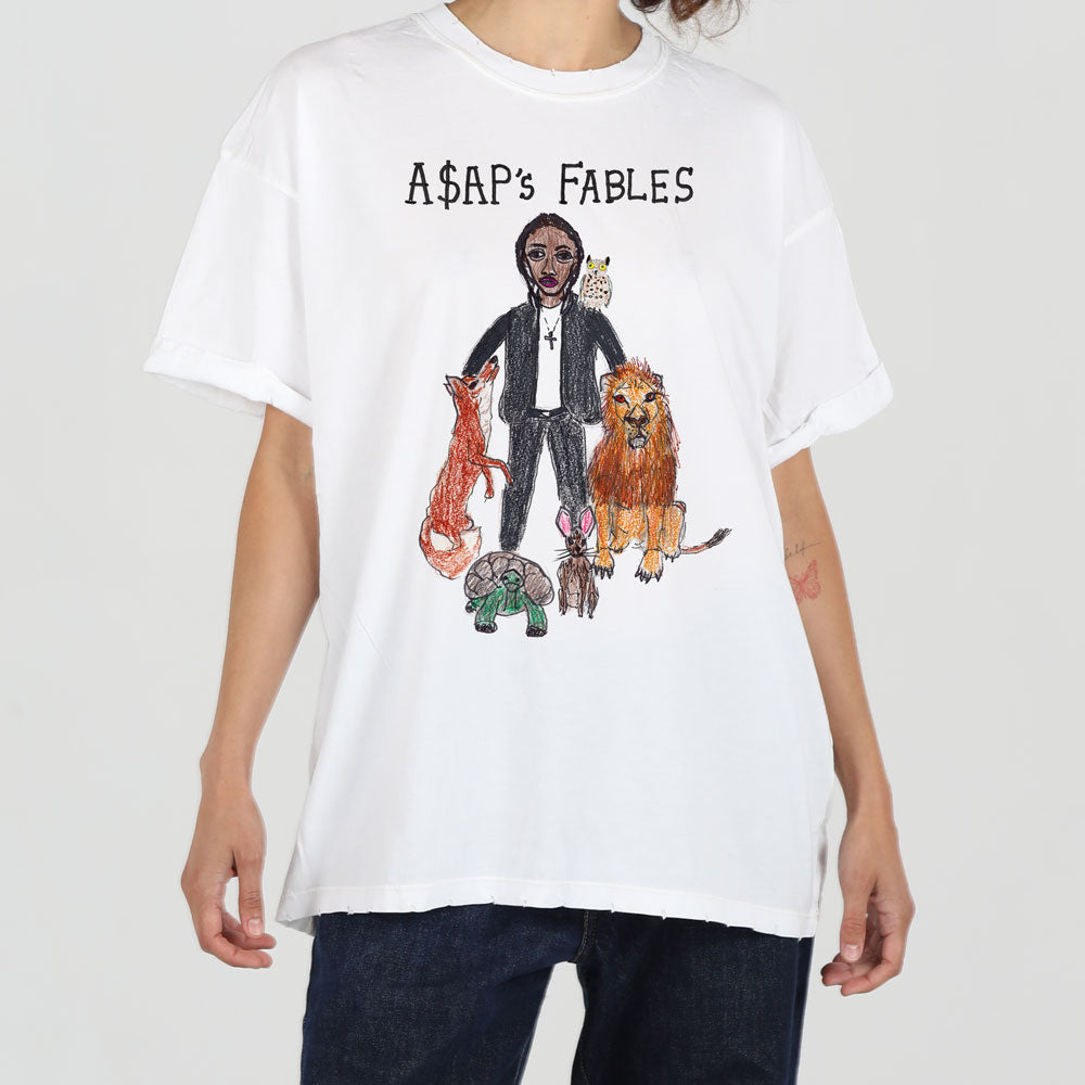 A person wearing a white t-shirt featuring illustrated characters from aesop's fables, including a man and various animals like a fox, lion, and turtle.