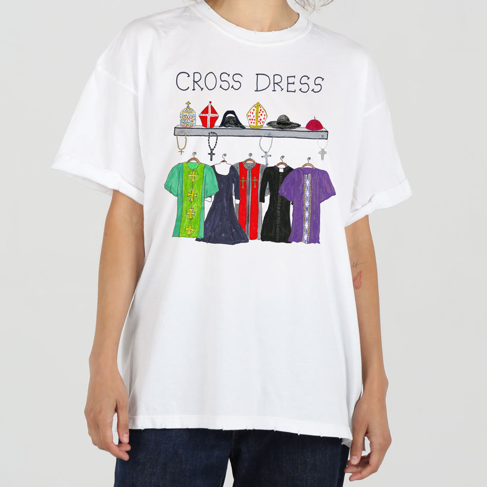 A person wearing a white t-shirt with the words "cross dress" over an illustration of various dresses and outfits hanging on a rack, including a robe and hats.