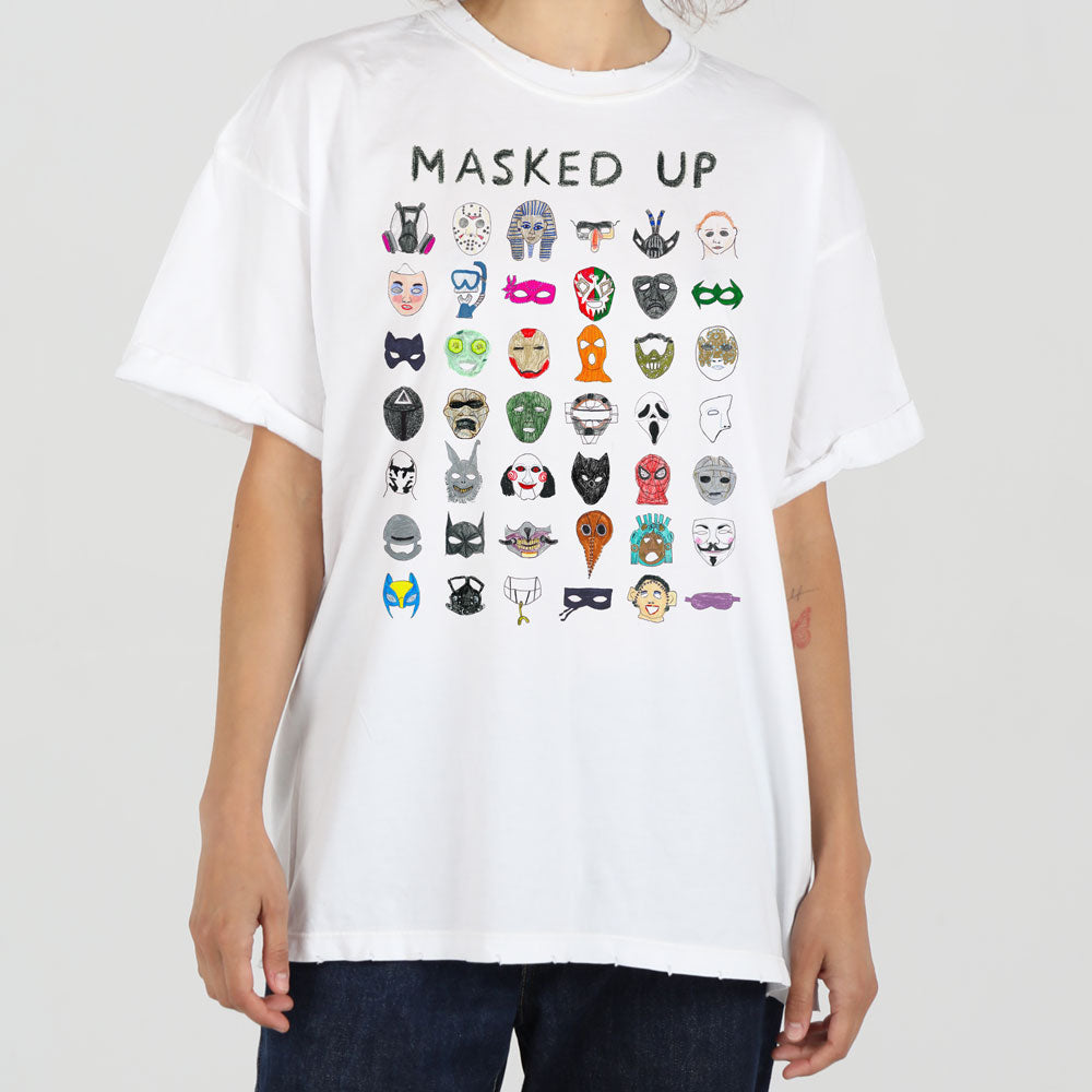 A person wearing a white t-shirt featuring colorful illustrations of various masks arranged in a grid pattern. the background is plain, emphasizing the shirt design.
