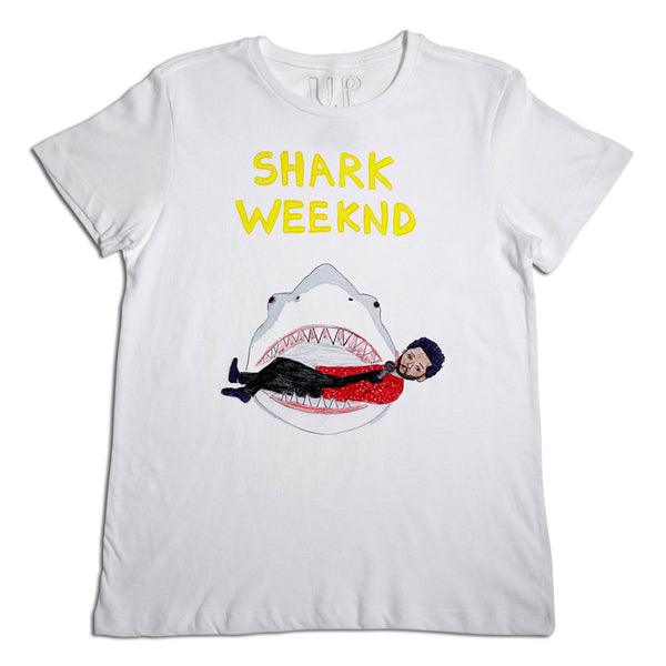 White t-shirt with a graphic design featuring a large shark with an open mouth, inside of which is a person wearing a red outfit. above the graphic, the text reads "shark weekend.