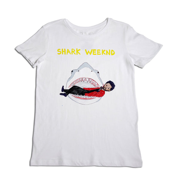 White t-shirt with a playful graphic print of a large shark's open mouth, inside which is a woman in a red bathing suit, surrounded by the words "shark weeknd" in yellow at the top.